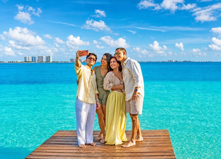 Friends taking a selfie on the pier over the turquoise sea at The Sens Cancun