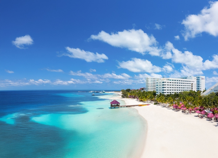 White sand beach with pier and palapa facing the Caribbean Sea at The Sens Cancun